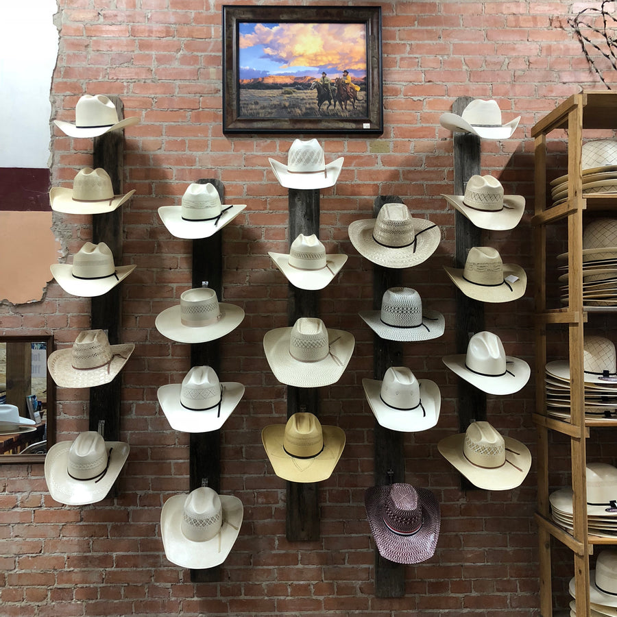 Rows of straw hats hanging on a brick wall display
