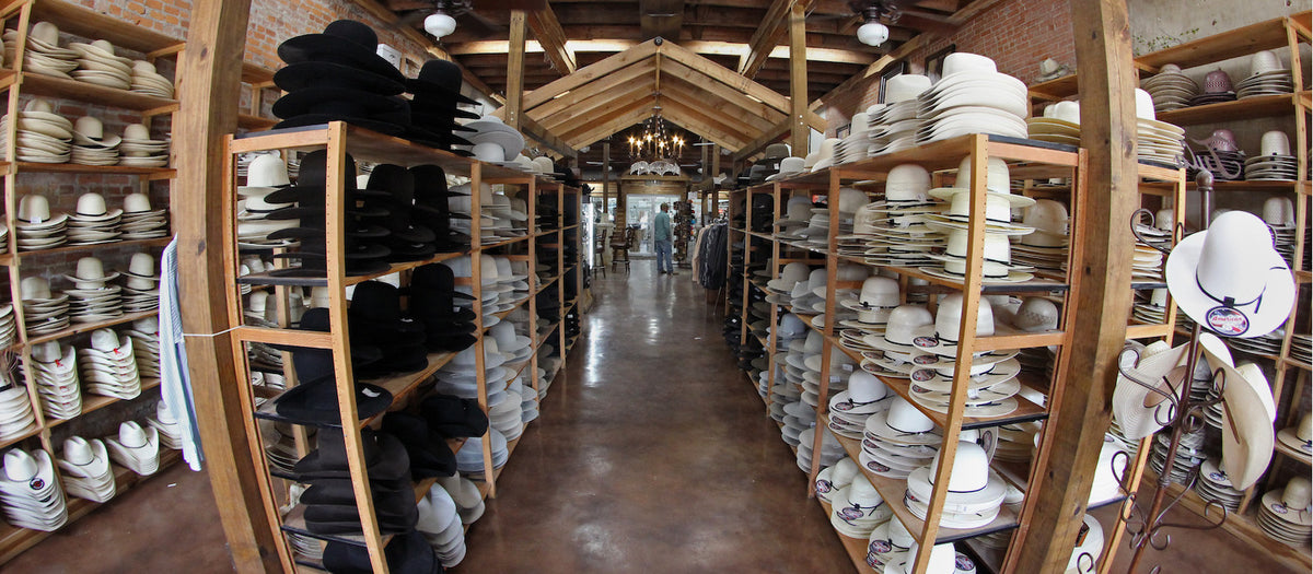Wide view of the shop floor lined with shelves of felt and straw hats